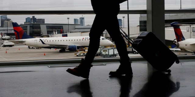 A passenger walks past a plane at a gate at Logan International Airport in Boston, Massachusetts, U.S., January 3, 2022. 