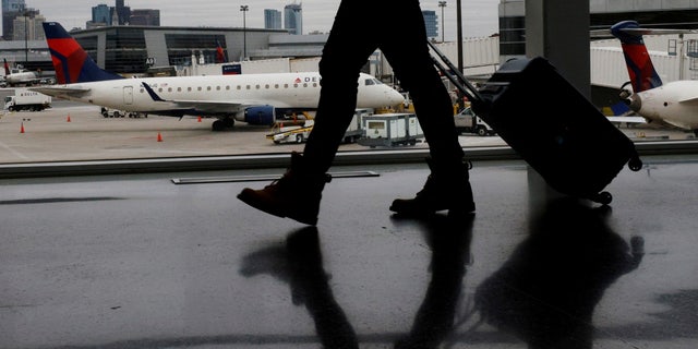 A passenger walks past a plane at a gate at Logan International Airport in Boston, Massachusetts, U.S., January 3, 2022.