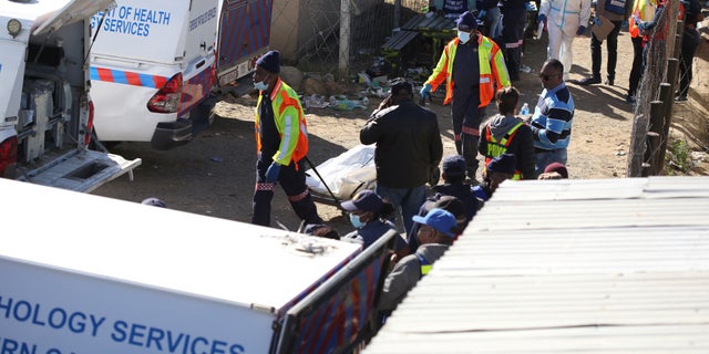 Forensic personnel load bodies of victims after the deaths of patrons found inside the Enyobeni Tavern, in Scenery Park, outside East London in the Eastern Cape province, South Africa, June 26, 2022. 