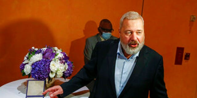 Nobel Peace Prize winner Dmitry Muratov standing with his award which auctioned for $103.5M.