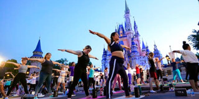 Nearly 2,000 Cast Members practice sunrise yoga celebrating International Yoga Day in front of Cinderella Castle at the Magic Kingdom Park at Walt Disney World Tuesday, June 21, 2022, in Lake Buena Vista, Fla. (AP Photo/John Raoux)