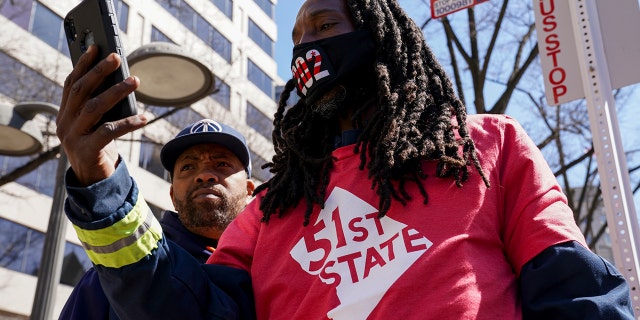 LaValle Gaston and Maurice Richardson hang 51-star flags at Black Lives Matter Plaza and along Pennsylvania Avenue on March 19, 2021, in Washington, D.C.