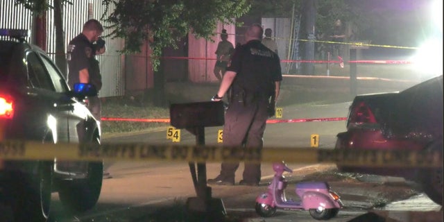 Harris County deputies stand near markers and a child bike at the scene where bullets were fired into a home Sunday night, killing a 7-year-old boy. 