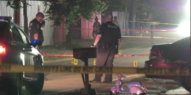 Harris County deputies stand near markers and a child bike at the scene where bullets were fired into a home Sunday night, killing a 7-year-old boy.