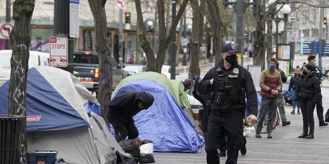 A Seattle police officer walks past tents on March 11 during the removal an encampment in Westlake Park in downtown Seattle.