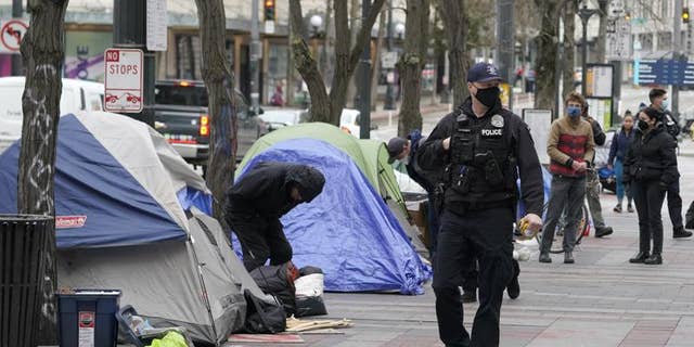 A Seattle police officer walks past tents on March 11 during the removal an encampment in Westlake Park in downtown Seattle.