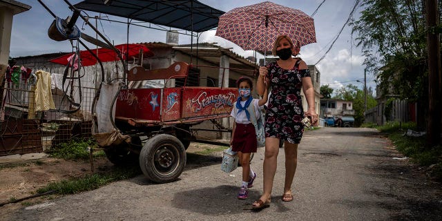 Danmara Triana walks home after picking up her daughter Alice from school in Cienfuegos, Cuba, Thursday, May 19, 2022. Triana's husband and son, who is Alice's father and brother, have lived in the U.S. since 2015, while she and their two daughters stayed behind. (AP Photo/Ramon Espinosa)