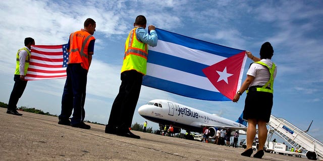 Airport workers receive JetBlue flight 387, the first commercial flight between the U.S. and Cuba in more than a half century, holding a United States, and a Cuban national flag, on the airport tarmac Wednesday, Aug. 31, 2016 in Santa Clara, Cuba. 