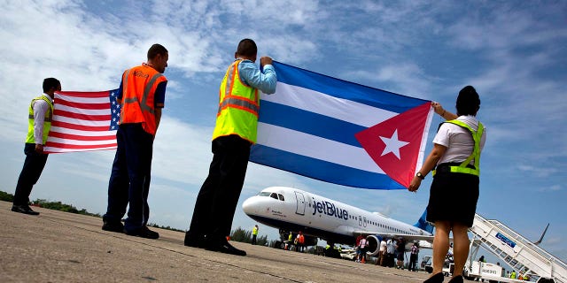 Airport workers receive JetBlue flight 387, the first commercial flight between the U.S. and Cuba in more than a half century, holding a United States, and a Cuban national flag, on the airport tarmac Wednesday, Aug. 31, 2016 in Santa Clara, Cuba. 