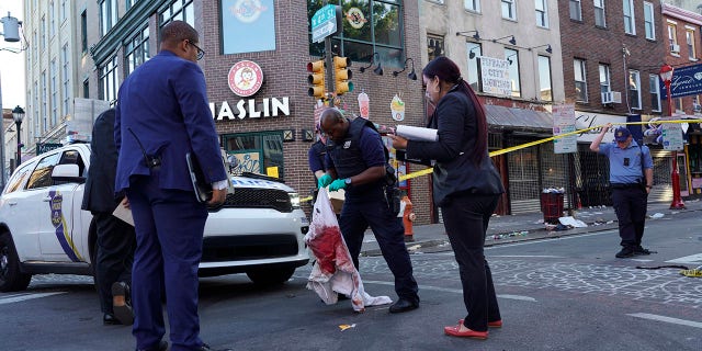 Philadelphia police work the scene of a fatal overnight shooting on South Street in Philadelphia, Sunday, June 5, 2022. Two people have been arrested and charged in the incident and a third is being sought, authorities sad Wednesday. 