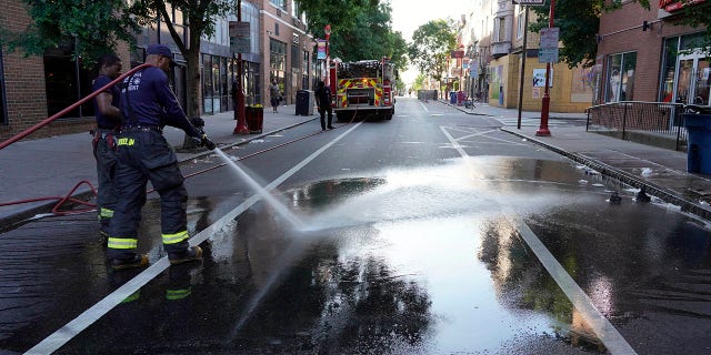 A Philadelphia firefighter washes blood off the sidewalk at the scene of a fatal overnight shooting on South Street in Philadelphia, Sunday, June 5, 2022. 