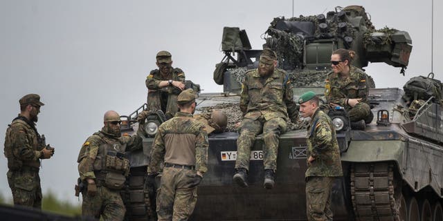 German Bundeswehr soldiers of the NATO enhanced forward presence battalion wait to greet German Chancellor Olaf Scholz ahead of his arrival at the Training Range in Pabrade, some 60km (38 miles) north of the capital Vilnius, Lithuania, Tuesday, June 7, 2022.