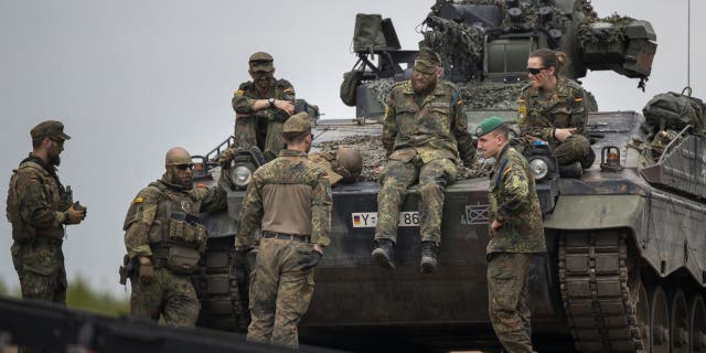 German Bundeswehr soldiers of the NATO enhanced forward presence battalion wait to greet German Chancellor Olaf Scholz ahead of his arrival at the Training Range in Pabrade, some 60km (38 miles) north of the capital Vilnius, Lithuania, Tuesday, June 7, 2022. 