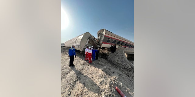 In this photo provided by Iranian Red Crescent Society, rescuers work at the scene where a passenger train partially derailed near the desert city of Tabas in eastern Iran, Wednesday, June 8, 2022. (Iranian Red Crescent Society via AP)
