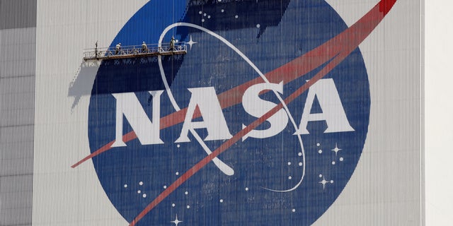 Workers on scaffolding repaint the NASA logo near the top of the Vehicle Assembly Building at the Kennedy Space Center in Cape Canaveral, Fla., Wednesday, May 20, 2020. 