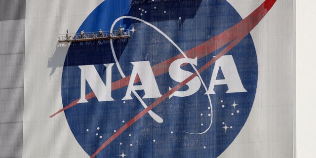 Workers on scaffolding repaint the NASA logo near the top of the Vehicle Assembly Building at the Kennedy Space Center in Cape Canaveral, Fla., Wednesday, May 20, 2020. 