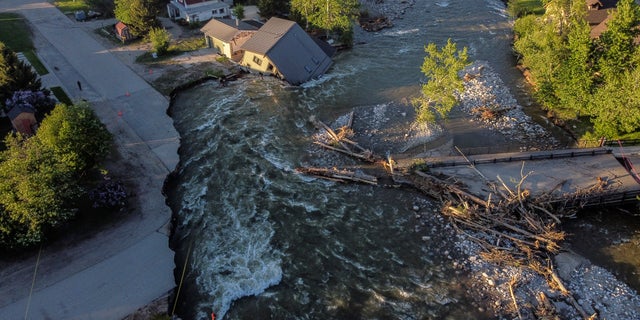 A house sits in Rock Creek after floodwaters washed away a road and a bridge in Red Lodge, Mont., Wednesday, June 15, 2022. 