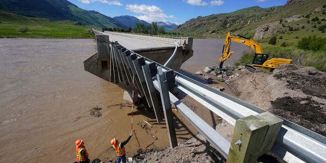 Highway workers inspect a washed out bridge along the Yellowstone River Wednesday, June 15, 2022, near Gardiner, Mont.