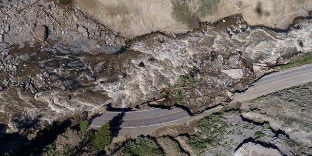 Receding floodwaters flow past sections of North Entrance Road washed away at Yellowstone National Park in Gardiner, Mont., Thursday, June 16, 2022.