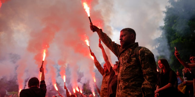 Soldiers hold flares as they attend the funeral for activist and soldier Roman Ratushnyi in Kyiv, Ukraine June 18, 2022.