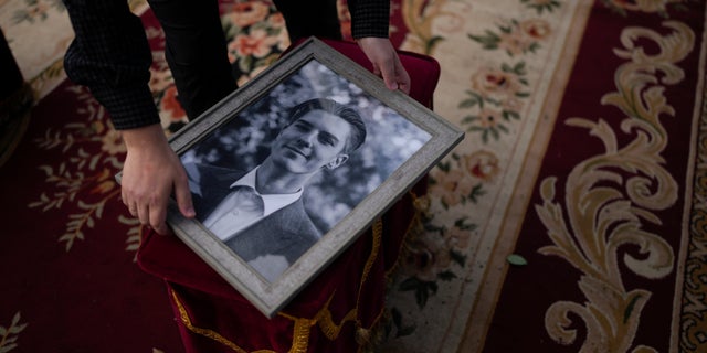 A man holds a photo of activist and soldier Roman Ratushnyi before the start of the memorial service in Kyiv, Ukraine, Saturday, June 18, 2022. Ratushnyi died in a battle near Izyum, where Russian and Ukrainian troops are fighting for control of the area. (AP Photo/Natacha Pisarenko)