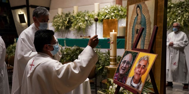 A priest blesses the photos of the two Jesuit priests who were killed by crime boss. 