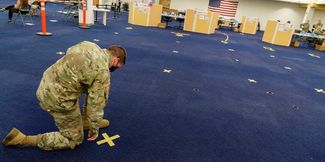 Army National Guard Staff Sgt. Andrew Bates pulls up tape marking a line at a coronavirus mass-vaccination site at the former Citizens Bank headquarters in Cranston, Rhode Island, on June 10, 2021.