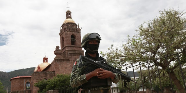 A Mexican soldier patrols outside the Church in Cerocahui, Mexico, following the murder of 2 priests and a tourist guide. 