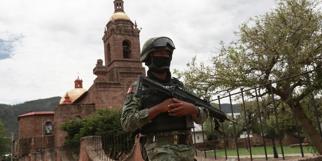 A Mexican soldier patrols outside the Church in Cerocahui, Mexico, following the murder of 2 priests and a tourist guide.