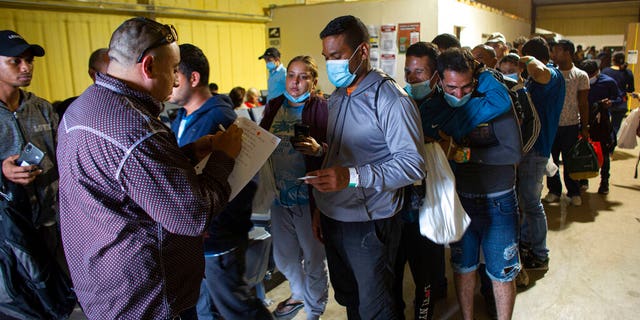 People line up for a commercial bus that will take them to the San Antonio airport at a warehouse run by the Mission: Border Hope nonprofit group run by the United Methodist Church in Eagle Pass, Texas, May 23, 2022. 