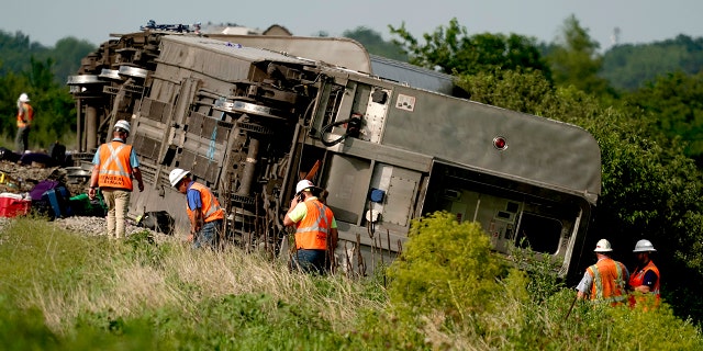 Workers inspect the scene of an Amtrak train which derailed after hitting a dump truck Monday, June 27, 2022, near Mendon, Mo.