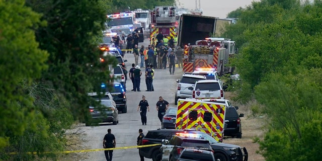 Police work the scene where dozens of people were found dead in a semitrailer in a remote area in southwestern San Antonio on Monday.