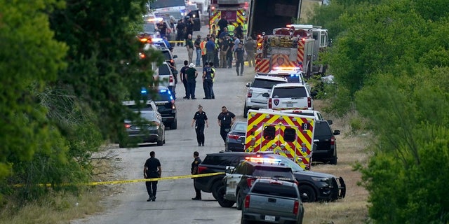 Police work the scene where dozens of people were found dead in a semitrailer in a remote area in southwestern San Antonio on Monday.