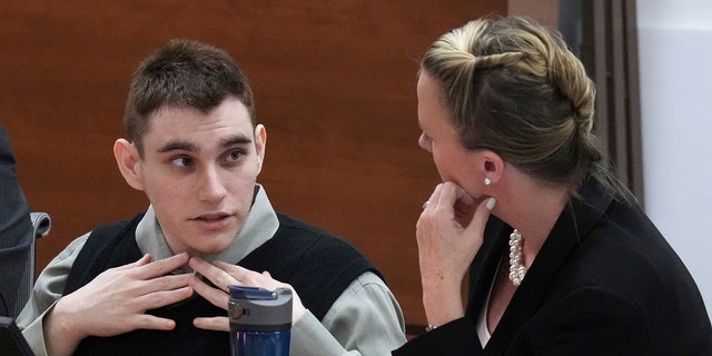 Marjory Stoneman Douglas High School shooter Nikolas Cruz fixes his collar as he speaks with Assistant Public Defender Melisa McNeill during jury selection in the penalty phase of his trial at the Broward County Courthouse in Fort Lauderdale on Tuesday, June 28, 2022. (Amy Beth Bennett/South Florida Sun Sentinel via AP, Pool)