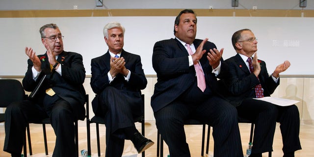 In this July, 24, 2012, file photo, John Sheridan, president and CEO of the Cooper Health System, left, applauds with George Norcross III, New Jersey Gov. Chris Christie and Dr. Paul Katz during an event in Camden, N.J. 