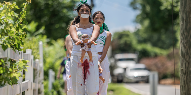 Abortion-rights activists with Rise Up 4 Abortion Rights chant after marching to the home of Supreme Court Justice Amy Coney Barrett on June 18, 2022 in Falls Church, Virginia. According to the Rise Up 4 Abortion Rights group, the dolls represent "forced births."