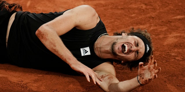 Germany's Alexander Zverev grimaces in pain after twisting his ankle during the semifinal match against Spain's Rafael Nadal at the French Open tennis tournament in Roland Garros stadium in Paris, France, Friday, June 3, 2022.