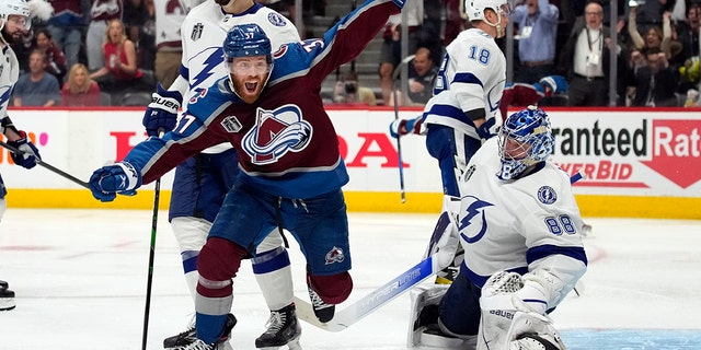 Colorado Avalanche's left-wing JT Compher (left) is Tampa Bay Lightning's goalkeeper Andrei after Andre Burakovsky scored an overtime goal in Game 1 of the NHL Hockey Tanley Cup Final in Denver on Wednesday, June 15, 2022. Celebrate next to Vasilevski.