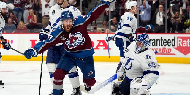 Colorado Avalanche left wing J.T. Compher, left, celebrates next to Tampa Bay Lightning goaltender Andrei Vasilevskiy, right, after an overtime goal by Andre Burakovsky in Game 1 of the NHL hockey Stanley Cup Final on Wednesday, June 15, 2022, in Denver.