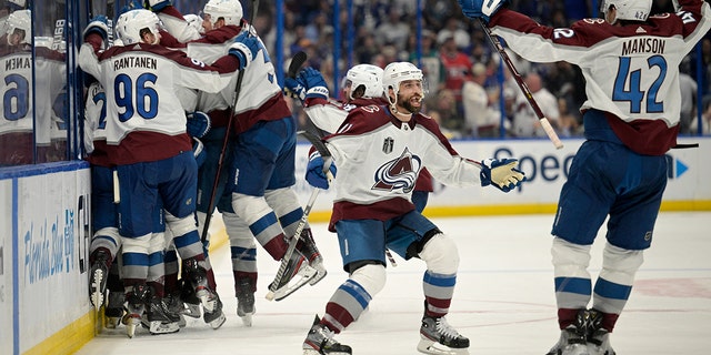 Colorado Avalanche center Andrew Cogliano, center, and defenseman Josh Manson (42) celebrate the overtime goal by teammate center Nazem Kadri (91) in Game 4 of the NHL hockey Stanley Cup Finals against the Tampa Bay Lightning on Wednesday, June 22, 2022, in Tampa, Fla.