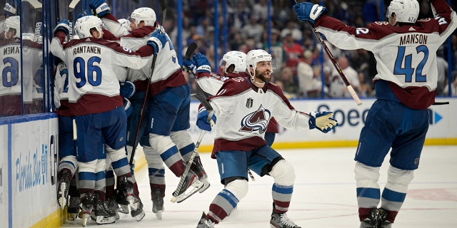 Colorado Avalanche center Andrew Cogliano, center, and defenseman Josh Manson (42) celebrate the overtime goal by teammate center Nazem Kadri (91) in Game 4 of the NHL hockey Stanley Cup Finals against the Tampa Bay Lightning on Wednesday, June 22, 2022, in Tampa, Fla.