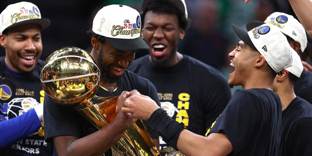 Andrew Wiggins, #22, and Jordan Poole, #3, of the Golden State Warriors celebrates with the Larry O'Brien Championship Trophy after defeating the Boston Celtics 103-90 in Game Six of the 2022 NBA Finals at TD Garden on June 16, 2022 in Boston, Massachusetts.