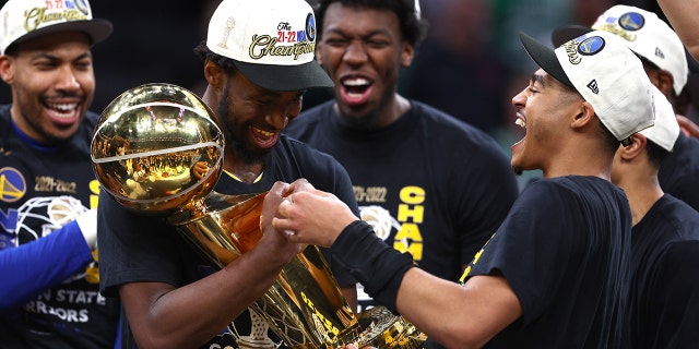 Andrew Wiggins, #22, and Jordan Poole, #3, of the Golden State Warriors celebrates with the Larry O'Brien Championship Trophy after defeating the Boston Celtics 103-90 in Game Six of the 2022 NBA Finals at TD Garden on June 16, 2022 in Boston, Massachusetts.