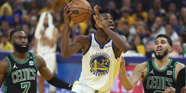 El alero de los Golden State Warriors Andrew Wiggins (22) dispara contra el portero de los Boston Celtics Jaylen Brown (7) y el alero Jayson Tatum (0) durante la primera mitad del Juego 5 de las Finales de la NBA en San Francisco el 13 de junio de 2022. 