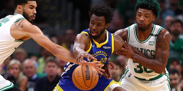 Jayson Tatum, left, and Marcus Smart, right, of the Boston Celtics battle for control of the ball with Andrew Wiggins of the Golden State Warriors during the first quarter of Game 6 of the 2022 NBA Finals at TD Garden in Boston June 16, 2022.