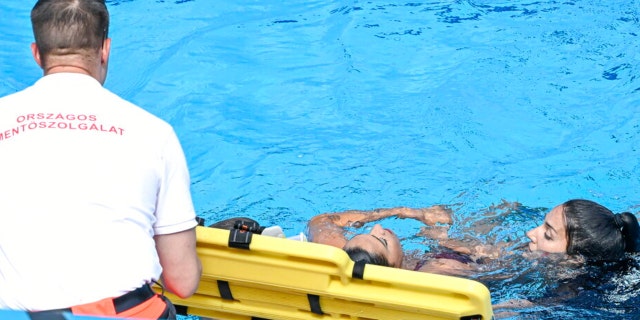 Anita Alvarez of United States, center, is taken from the pool after collapsing during the solo free final of the artistic swimming at the 19th FINA World Championships in Budapest, Hungary, Wednesday, June 22, 2022.  