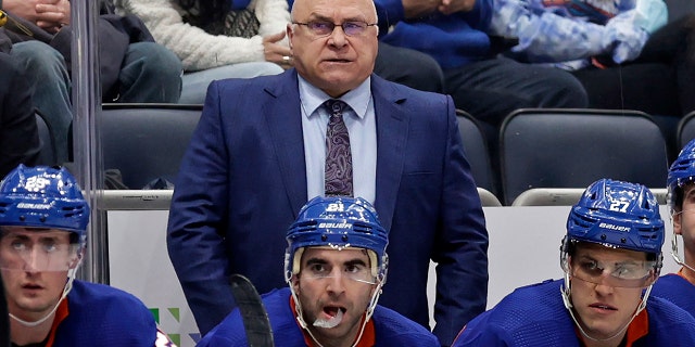FILE - New York Islanders head coach Barry Trotz, top, looks on in the third period of an NHL hockey game against the Minnesota Wild, Jan. 30, 2022, in Elmont, N.Y.