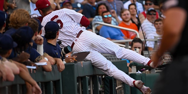 Jun 19, 2022; Omaha, NE, USA; Oklahoma Sooners first baseman Blake Robertson (26) dives into the dugout to catch a ball against the Notre Dame Fighting Irish in the first inning at Charles Schwab Field.