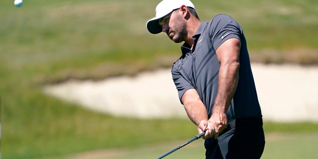 Brooks Koepka chips a shot onto a green during a practice round ahead of the U.S. Open golf tournament, Tuesday, June 14, 2022, at The Country Club in Brookline, Mass.