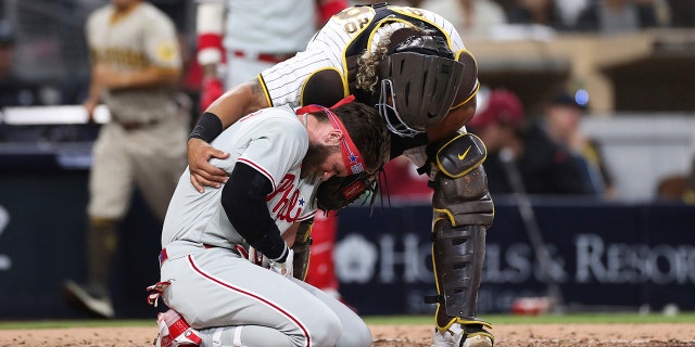 Philadelphia Phillies' Bryce Harper reacts after being hit by San Diego Padres pitcher Blake Snell's pitch, as Padres catcher Jorge Alfaro checks in on him Saturday, June 25, 2022 in San Diego. 